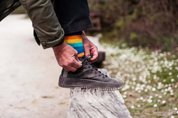 walker man tying his shoes - close up of a pair of sneakers on a wooden plank