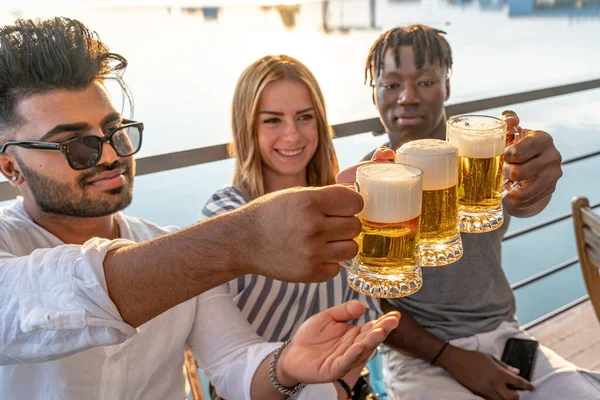 成群结队的年轻人多民族朋友在河里举着三杯啤酒祝酒 在船上度过暑假 — 图库照片