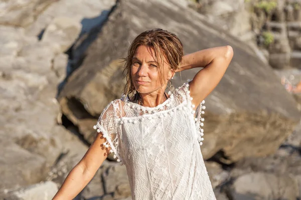 海の岩の上にポーズ白いシャツを着ている美しいブロンドの女性 — ストック写真