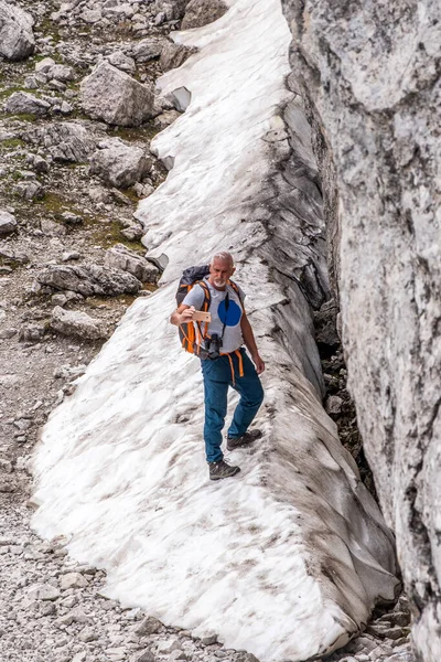 経験豊富な成熟した男性のハイカーは イタリアのドロミテの雪の谷を登っています — ストック写真
