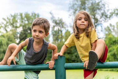 twins boys and girls have fun climbing metal pipes to play and screaming