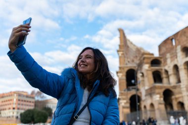Mutlu orta yaşlı kadın Roma 'daki kolezyum amfitiyatrosunun önünde selfie çekiyor. Eğlence ve tatil konsepti..
