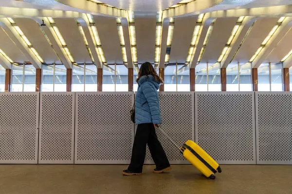 漂亮的中年女商人带着黄色推车在机场走廊里散步度假 旅行和度假的概念 — 图库照片