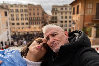 Mutlu orta yaşlı turistler Roma eğlence ve tatil konseptinde ünlü Trinit Dei Monti merdiveninin önünde selfie çekiyorlar.