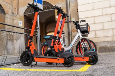 Şehirdeki kentsel park alanında elektrikli scooter ve elektrikli bisiklet kiralama hizmetleri - sürdürülebilir kentsel ulaşım kavramı
