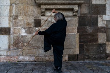 Orta yaşlı Tai Chi ustası bir ortaçağ katedralinin mimarisinin ortasında sopa egzersizleri gösteriyor.