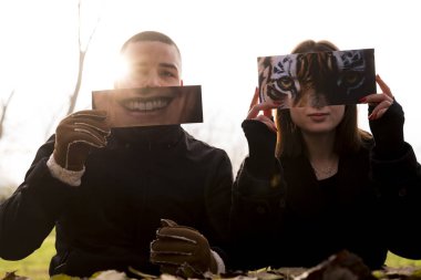 İki genç aşığın portresi, kışın bir halk parkında kısmen yüzlerini kaplayan fantezi resimlerini göstererek eğleniyor.