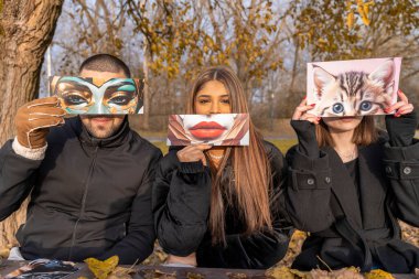 Bir grup insanın kışın bir halk parkında kısmen yüzlerini kaplayan bir fantezi görüntüsünü göstererek eğlendikleri portre.