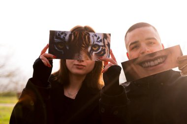 İki genç aşığın portresi, kışın bir halk parkında kısmen yüzlerini kaplayan fantezi resimlerini göstererek eğleniyor.