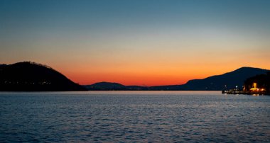 Iseo Gölü 'nün mavi sularında güzel bir günbatımı manzarası. Arka planda bir kış günü sıradağları var.