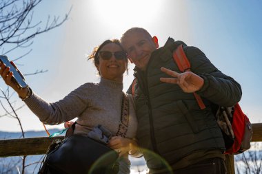 Güzel orta yaşlı çift, dağlarda yürürken selfie çekiyor.