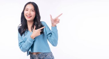 Cheerful excited asian woman use finger pointing to side with product or empty copy space standing over isolated white background. Model young girl laughing promotion. Advertisement presenting concept