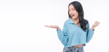 Confident smile asian woman raised up hand on empty standing on white background. Excited joy young girl showing copy space on hand presenting product over isolated. Advertisement presentation concept