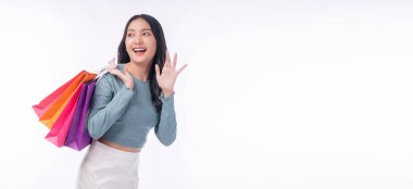 Enjoyment excited asian woman carry shopping bags standing on white background. Trendy happy shopper consumer carefree young girl holding shopping paper bags with copy space over isolated background.