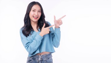 Cheerful excited asian woman use finger pointing to side with product or empty copy space standing over isolated white background. Model young girl laughing promotion. Advertisement presenting concept