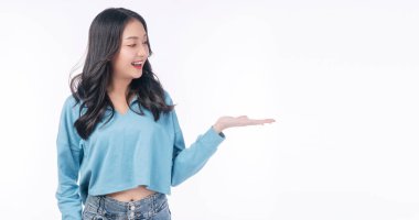 Confident smile asian woman raised up hand on empty standing on white background. Excited joy young girl showing copy space on hand presenting product over isolated. Advertisement presentation concept