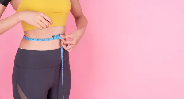 ピンクの背景に測定テープウエストラインを使用してスリムボディアジアの女性 形の若い少女の測定のウエストライン減量の成功は孤立したパステル背景に ヘルスケアダイエット完璧な薄いボディ — ストック写真