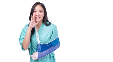 Yaralı Asyalı bir kadın beyaz arka planda el üstünde ağız ilanı veriyor. Heyecanlı kadın yaralanması, acı verici bir kaza, kırık el ateli kol, izole edilmiş sağlık sigortası, iyi haber..