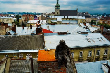 Bronz bir baca heykeli fotoğrafı Lviv 'de güzel manzaralı bir evin çatısını temizliyor.