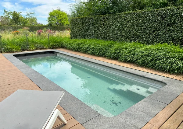 Yüzme havuzu ve terasta güneş paneli. Tahta döşeme. Süslü çimen kenarı