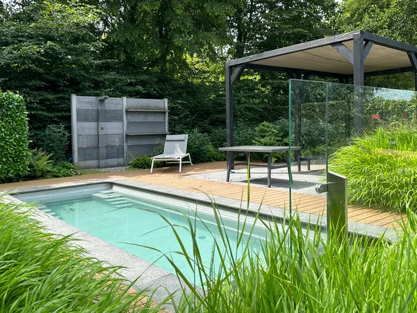 Başvuru, Hollanda, 11 Temmuz 2023, havuz. Güneş paneli ve alüminyum pergola. Tahta döşeme. Süslü çimen kenarı