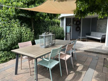 Apeltern, Hollanda, 11 Temmuz 2023, Appeltern macera bahçesi. Gölgelik yelkenli, bahçe sandalyeli ve ahşap masalı yaz terası. Tahta döşemeli ahşap çardak.