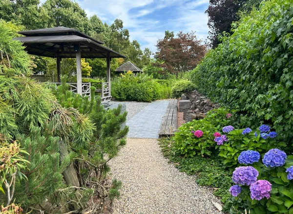 Apeltern, Hollanda, 11 Temmuz 2023, Appeltern macera bahçesi. Oymalı asfalt, çay çardağı, çiçek açan ortanca ve geleneksel doğu bitkileriyle doğu manzarası.