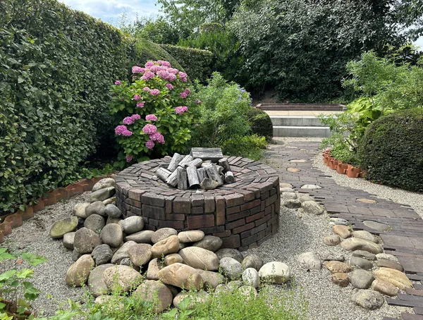 Apeltern, Hollanda, 11 Temmuz 2023, Appeltern macera bahçesi. Eski moda asfalt desenli yaz bahçesi, boxwood ve şömine.