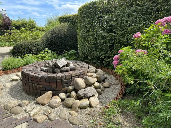 Apeltern, Hollanda, 11 Temmuz 2023, Appeltern macera bahçesi. Eski moda asfalt desenli yaz bahçesi, boxwood ve şömine.