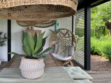 Apeltern, Hollanda, 11 Temmuz 2023, Appeltern macera bahçesi. Yumurta şeklindeki rattan efektli koltuk ve hasır bahçe mobilyalarıyla güzel bir bahçe terası. Plaj tarzı