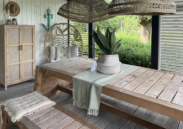 Apeltern, Hollanda, 11 Temmuz 2023, Appeltern macera bahçesi. Ahşap masası ve rattan mobilyası olan bir veranda. Rahatlamak için rahat bir yer.