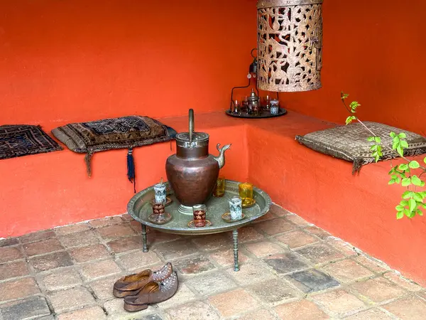Fas çardağı. Masadaki kahve seti. Turuncu kil duvarlar, sıralarda yastıklar. Fransa 'daki Kerfouler Bahçeleri