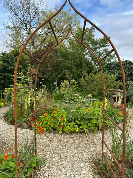 Organik bir bahçede paslı metal kemer. Bu bahçe doğal olarak zararlıları ve hastalıkları önlemek için sebze, meyve ve çiçeklerin dönüşümünü kullanır. Kerfouler Bahçeleri, Fransa