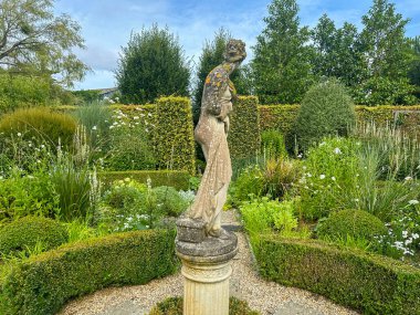 Plouc-du-Trieux, France, July 24, 2024: Gardens Kerfouler. A classical garden scene featuring lush greenery and a central statue of Helen of Troy, framed by carefully trimmed hedges and pathways clipart