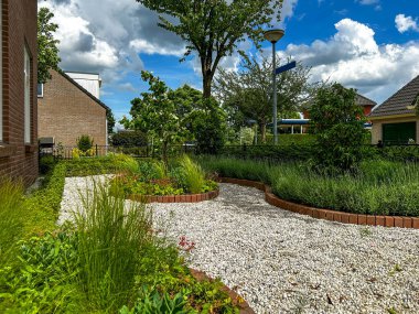 Decorative gravel paths and tidy perennial planting in a front garden.Includes lavender, ornamental grasses, Sedum, Geranium macrorrhizum, and Stipa lessingiana. Gaanderen, Netherlands