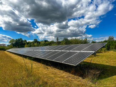 Geniş bir alanda güneş panelleri. Bulutlu mavi gökyüzünün altında yenilenebilir enerji sistemi. Hollanda Hengelo 'daki halk güneş parkı