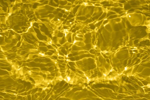 焦点は スプラッシュや泡と透明な金色の澄んだ穏やかな水の表面の質感をぼやけている 傾向の抽象的な性質の背景 コピースペースと日光の水の波 金箔の輝き — ストック写真