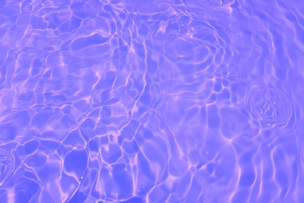 焦点は スプラッシュ 泡と透明な紫色の透明色の澄んだ穏やかな水の表面のテクスチャをぼかした 輝く紫色の水のリップルの背景 スイミングプールでの水の表面 熱帯紫色の水の色 — ストック写真