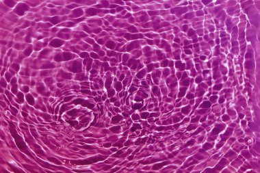 Defocus bulanık, şeffaf mor renkte berrak, durgun su yüzeyi dokusu sıçrama ve kabarcıklarla bulanıklaştırılmış. Moda soyut doğa geçmişi. Güneş ışığında fotokopi uzayıyla birlikte su dalgaları. Pembe suluboya