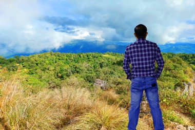 portre yakışıklı adam dağda duruyor ve gökyüzüne bakıyor bir bulutlu sabah macerası konseptiyle.