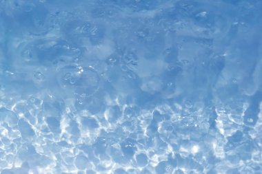 Defocus bulanık mavi şeffaf, berrak, durgun su yüzeyi dokusu sıçrama ve kabarcıklarla bulanıklaştırılmış. Moda soyut doğa geçmişi. Güneş ışığında fotokopi uzayıyla birlikte su dalgaları. Mavi suluboya parlıyor