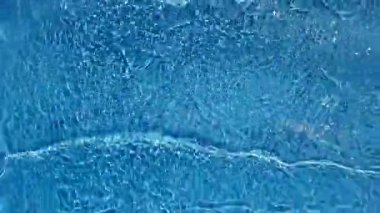 Defocus bulanık mavi şeffaf, berrak, durgun su yüzeyi dokusu sıçrama ve kabarcıklarla bulanıklaştırılmış. Moda soyut doğa geçmişi. Güneş ışığında fotokopi uzayıyla birlikte su dalgaları. Mavi suluboya parlıyor