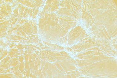 Defocus bulanık, şeffaf altın rengi berrak, sakin su yüzeyi dokusu sıçrama ve kabarcıklarla bulanıklaştırılmış. Moda soyut doğa geçmişi. Güneş ışığında fotokopi uzayıyla birlikte su dalgaları. Sarı suluboya parlıyor