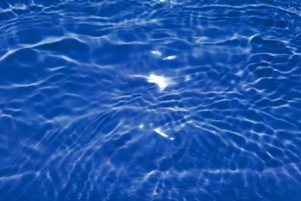 焦点がぼやけた透明ブルーの透明感のある透明感のある穏やかな水面の質感とスプラッシュと泡 傾向の抽象的な性質の背景 コピースペースと日光の水の波 青い水彩の輝き — ストック写真