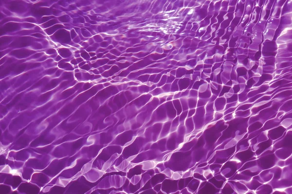 stock image Defocus blurred transparent purple colored clear calm water surface texture with splashes and bubbles. Trendy abstract nature background. Water waves in sunlight with copy space. Pink water drop shine