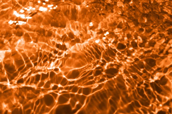 Defocus模糊了透明的红色橙色清晰平静的水面纹理与水花和气泡 潮流抽象的自然背景 阳光下的水波有复制空间 红色橙色水彩斑斓 — 图库照片