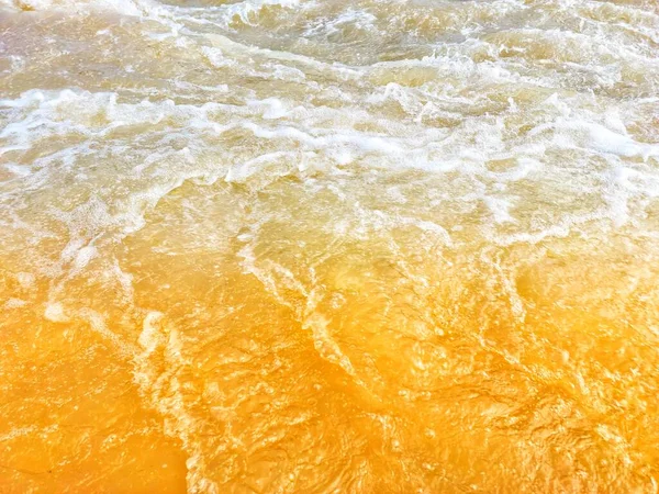 Defocus blurred transparent orange colored clear calm water surface texture with splash, bubble. Shining orange water ripple background. Surface of water in swimming pool. Orange bubble water, splash.