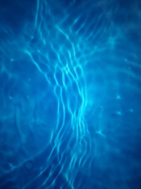 Defocus bulanık mavi şeffaf, berrak, durgun su yüzeyi dokusu sıçrama ve kabarcıklarla bulanıklaştırılmış. Moda soyut doğa geçmişi. Güneş ışığıyla birlikte su dalgaları. Mavi su parlıyor 