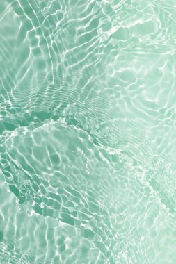 Defocus bulanık, şeffaf yeşil renkli berrak, durgun su yüzeyi dokusu sıçrama ve kabarcıklarla bulanıklaştırılmış. Moda soyut doğa geçmişi. Güneş ışığıyla birlikte su dalgaları. Yeşil su parlıyor