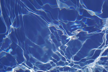 Defocus bulanık mavi şeffaf, berrak, durgun su yüzeyi dokusu sıçrama ve kabarcıklarla bulanıklaştırılmış. Moda soyut doğa geçmişi. Güneş ışığıyla birlikte su dalgaları. Mavi su parlıyor 